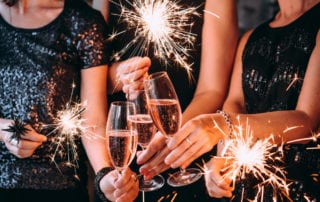 People holding champagne glasses and sparklers celebrating New Years.